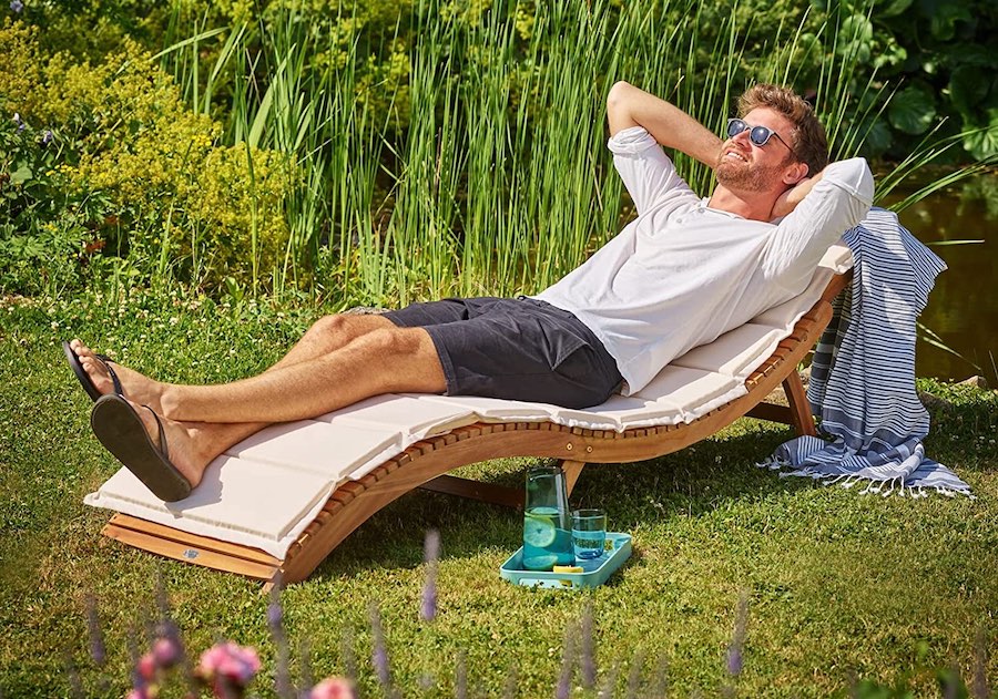 Mann sitzt auf Holz-Sonnenliege aus Akazie